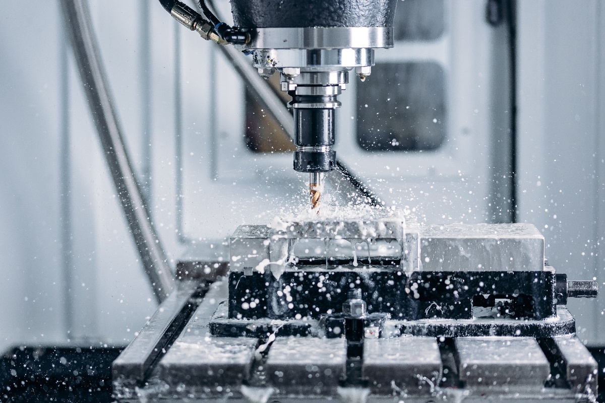 Close-up of CNC milling machine using coolant spray to wash away metal chips from the cutting area.