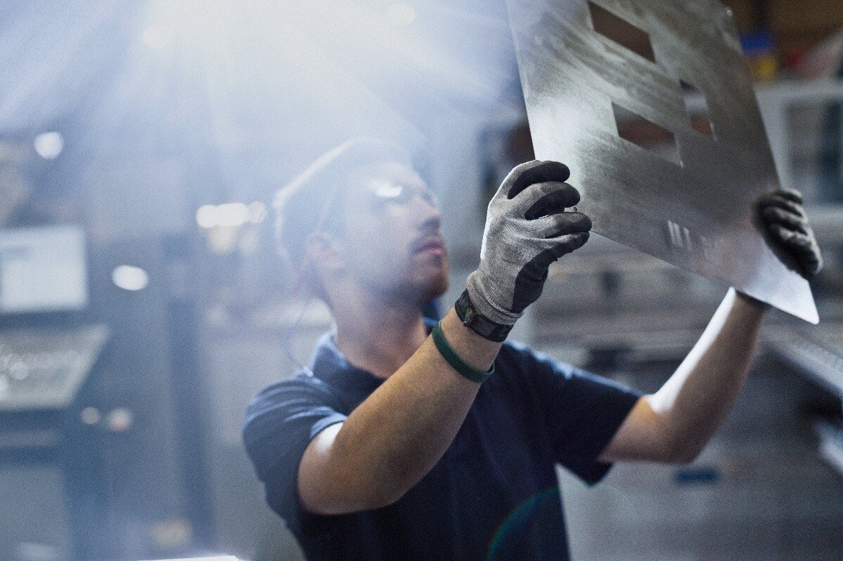 Machinist inspecting a sheet metal part for quality control.